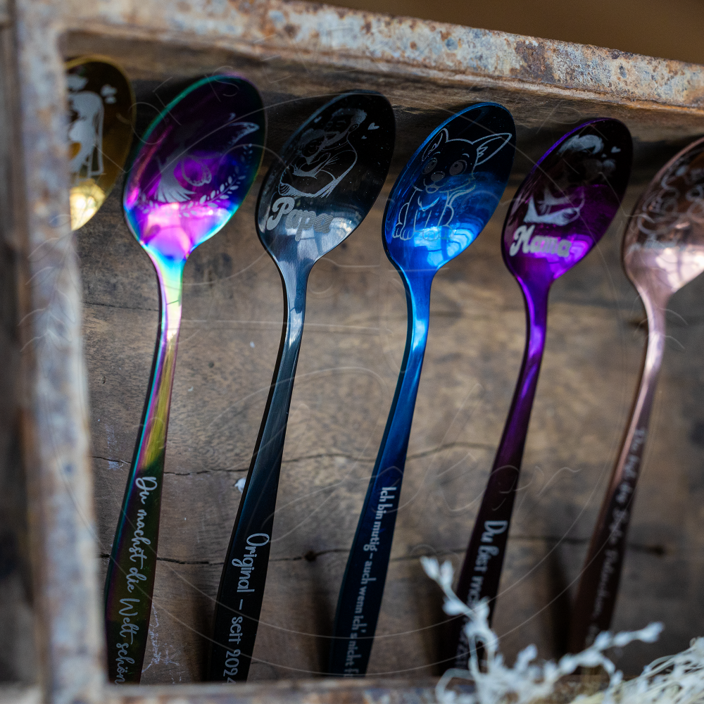 Mehrere personalisierte Kinderlöffel mit Lasergravur und Namen in verschiedenen Farben, dekorativ angeordnet