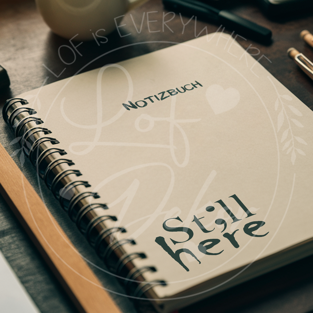 Notizbuch mit dem Schriftzug ‚St;ll here‘, emotionales Motiv für mentale Gesundheit auf Schreibtisch